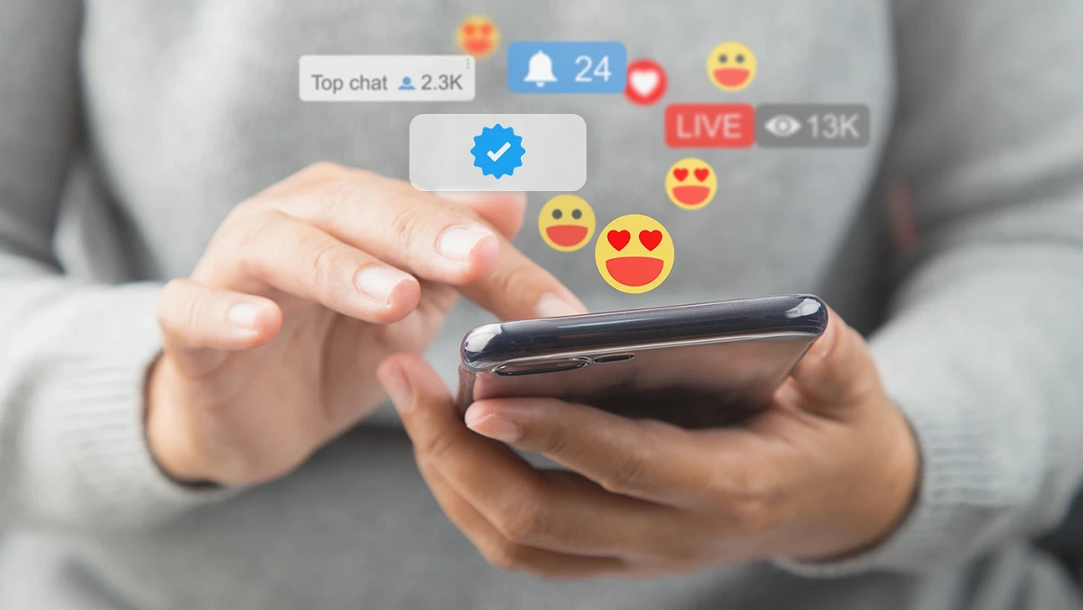 Social Media: Person interagiert am Telefon mit Emoticons