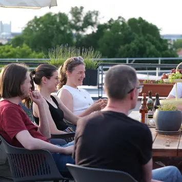 Das Team sitzt auf der Terasse am Tisch. 